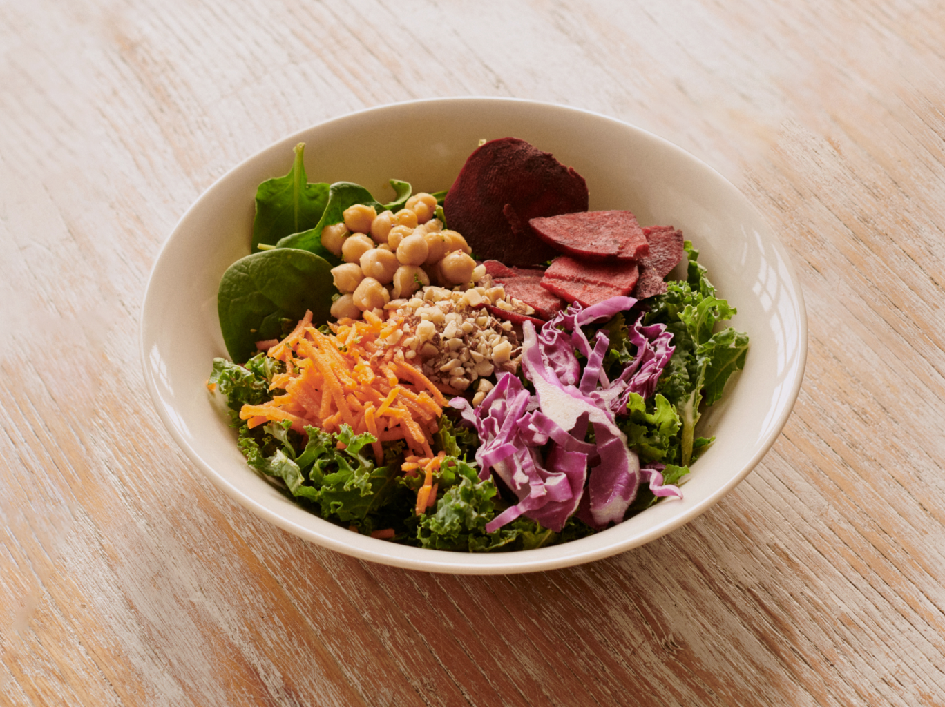 A salad that fully embodies health and wellness made of spinach, kale, cabbage, chickpeas, carrots, and beets.
