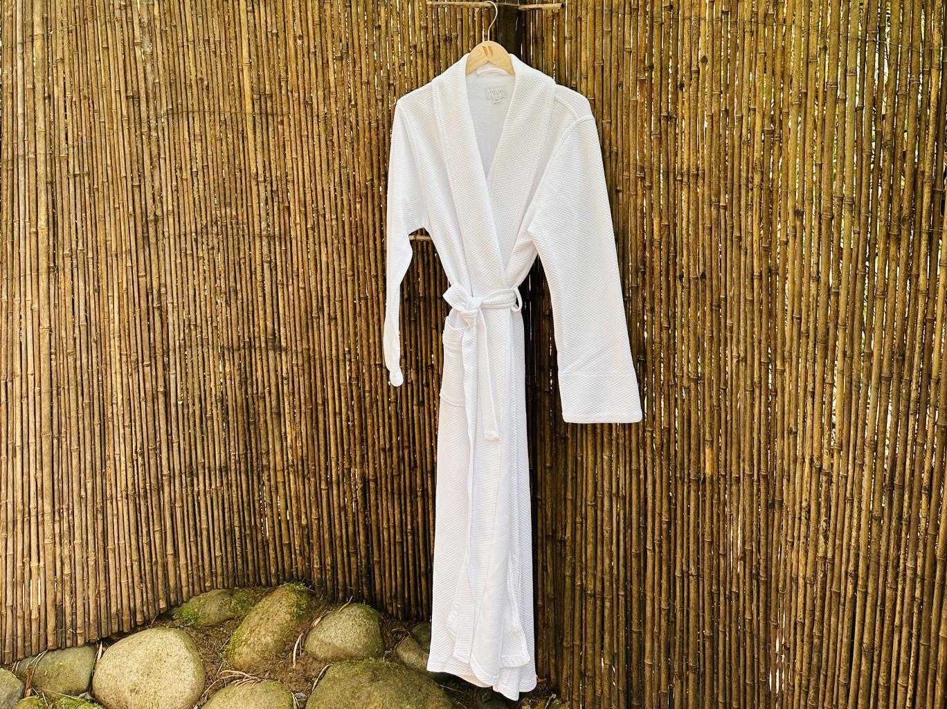 One white robe hanging against a wall of bamboo