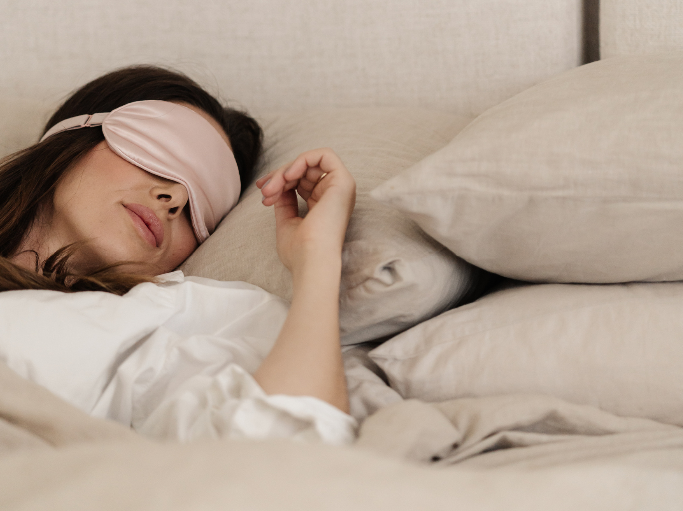 A female entrepreneur on vacation in the new year and resting in bed with an eye mask on, in order to prioritize her mental health, prevent burnout and create healthy habits.